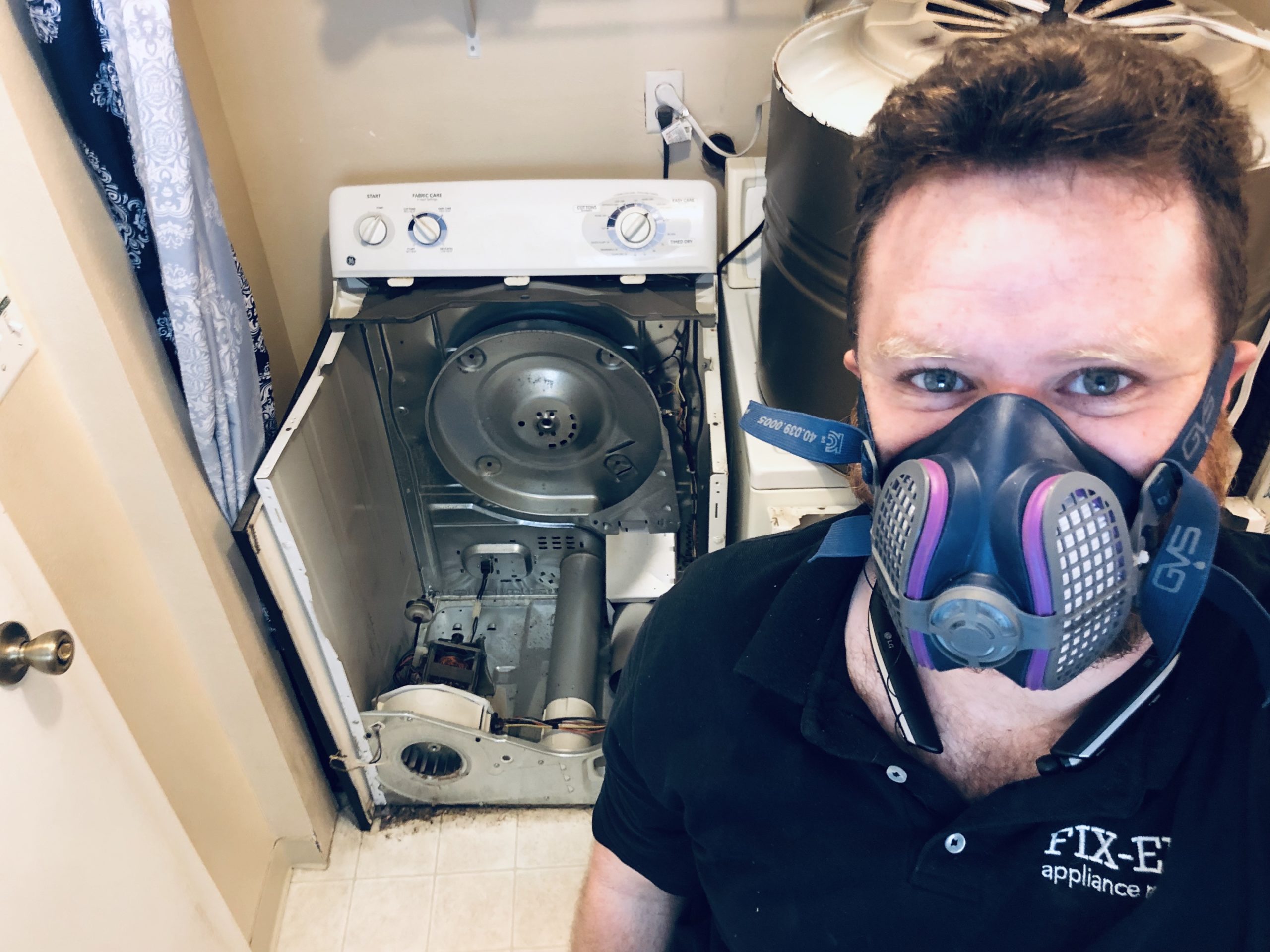A technician standing in front of a dryer that needed maintenance.