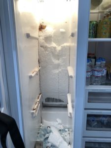 A frozen freezer inside a refrigerator.