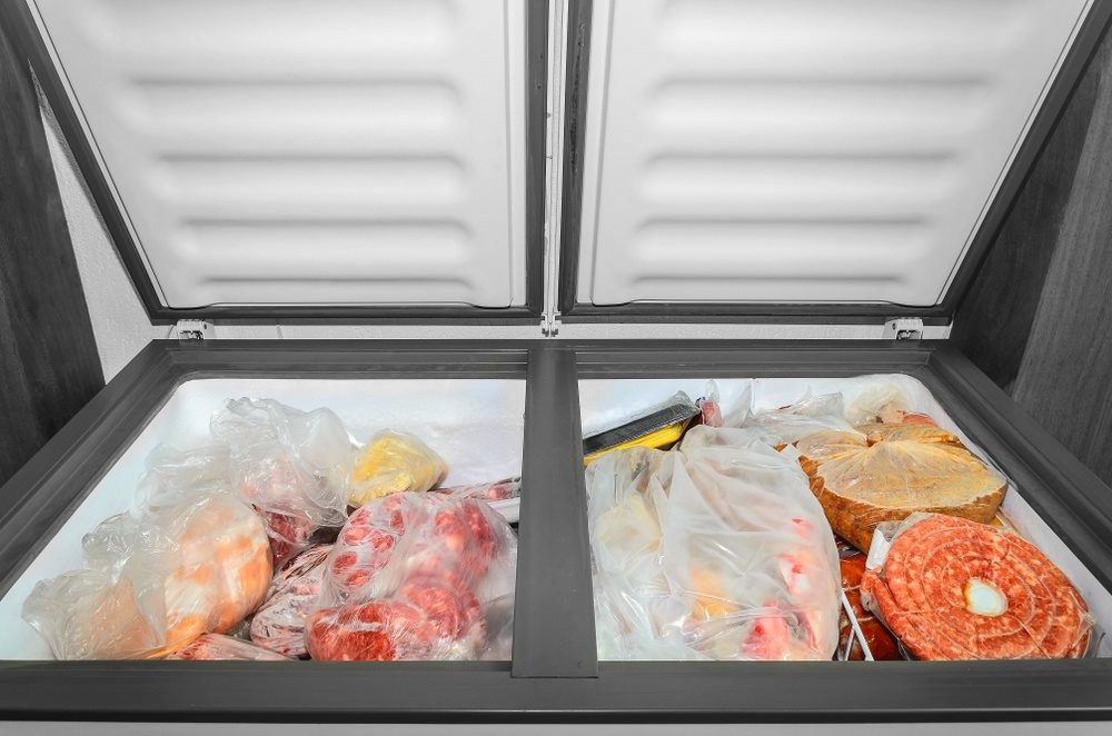 Open freezer with frozen meat and produce