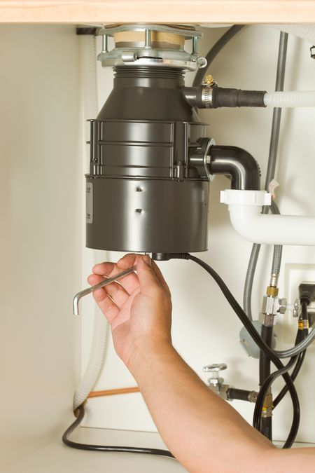 A technician repairing a garbage disposal.