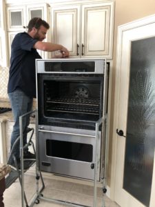 A technician performing a repair on an oven.