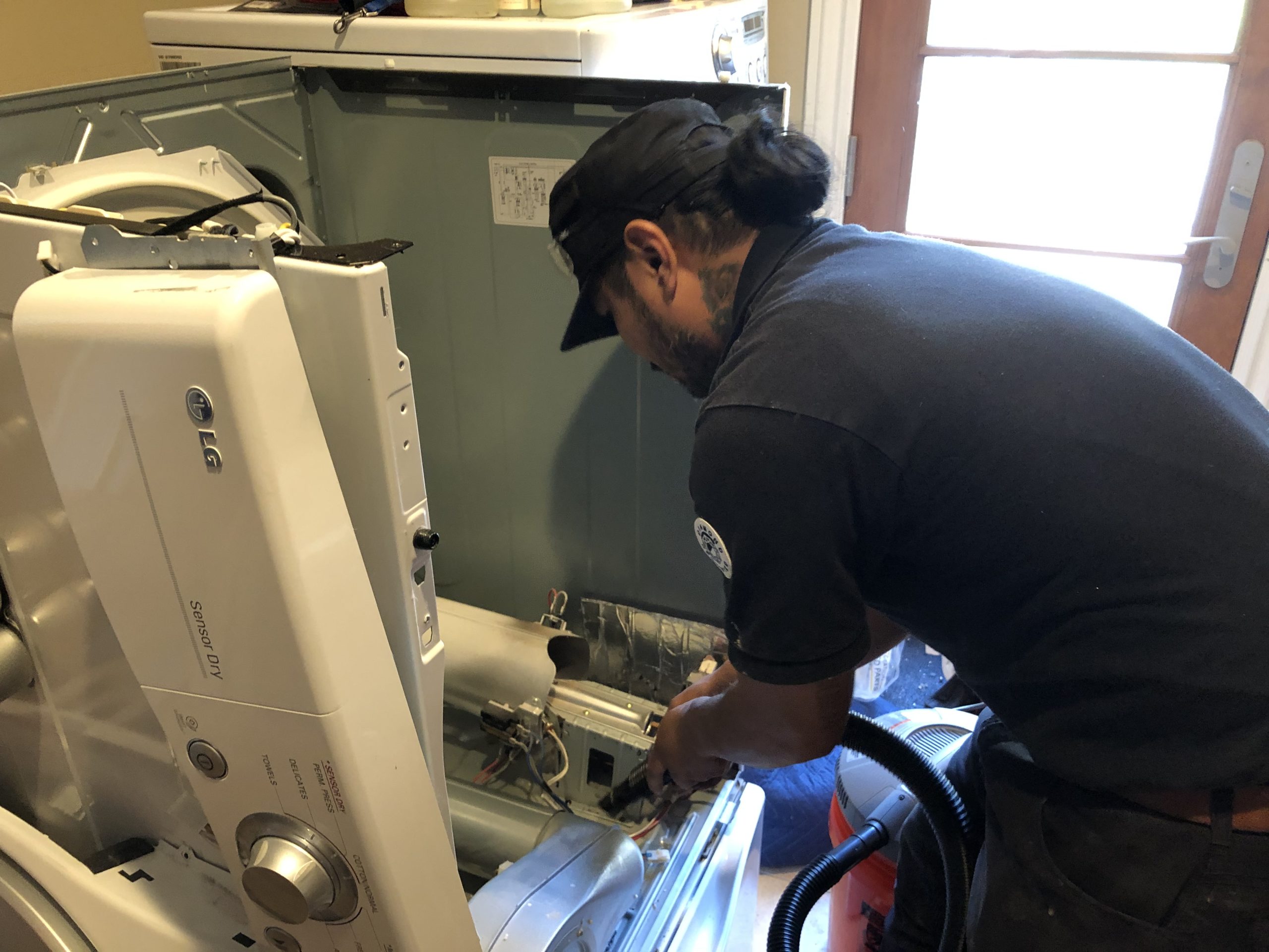 A technician repairing a gas dryer