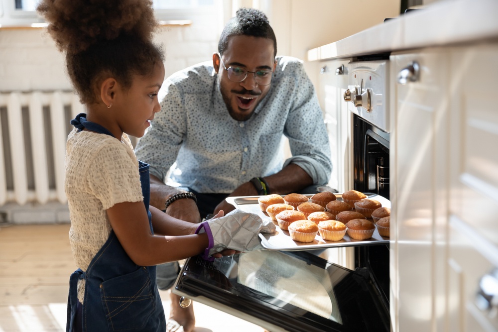 Father and daughter baking muffins in the oven for the holidays