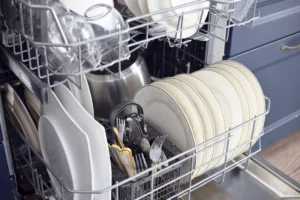 an open dishwasher full of dishes (square plates, round plates, silverware, wine glasses, and small dessert plates)
