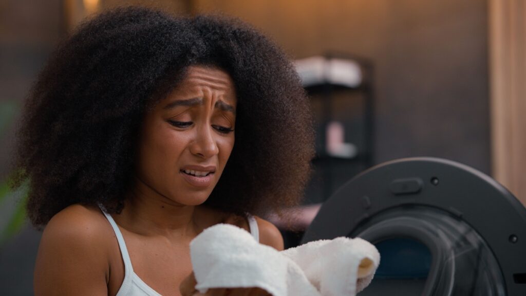 woman pulling towels from the dryer and notices they smell like something burning