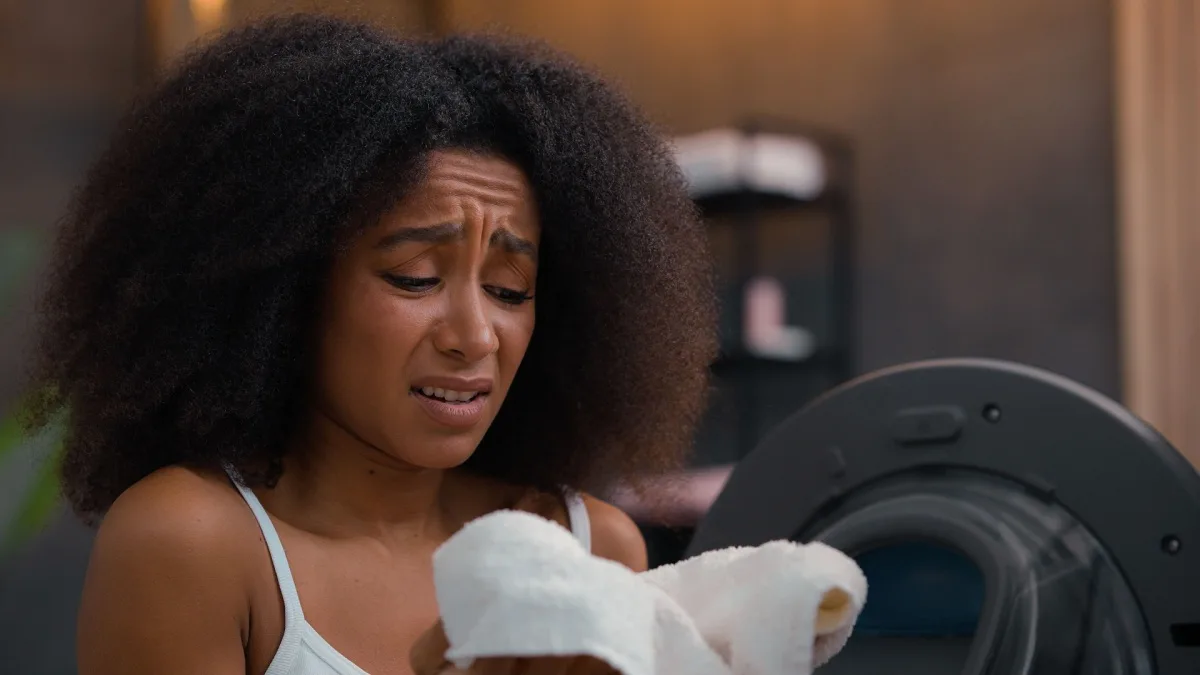 woman pulling towels from the dryer and notices they smell like something burning