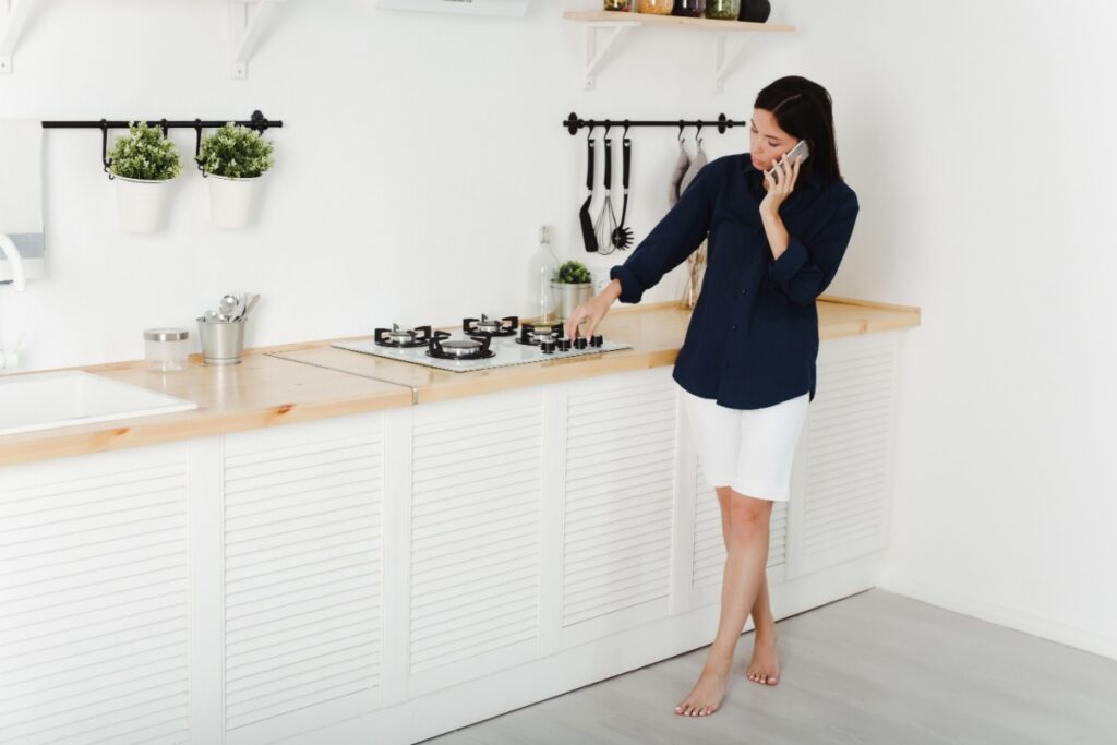 A woman on the phone with a technician as she tries to get her gas cooktop to ignite