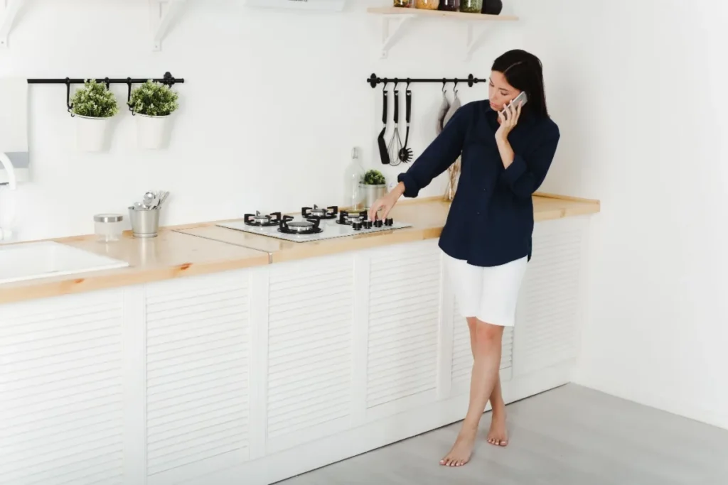 A woman on the phone with a technician as she tries to get her gas cooktop to ignite