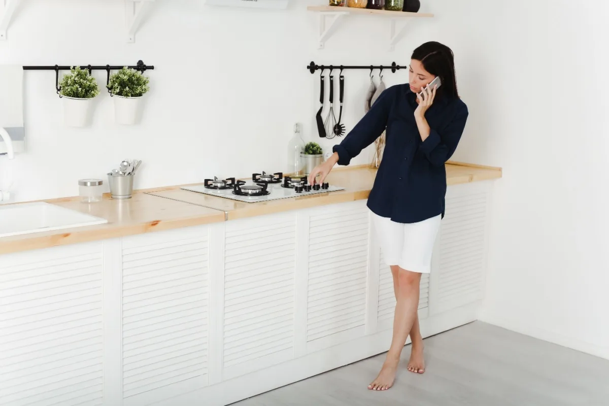 A woman on the phone with a technician as she tries to get her gas cooktop to ignite