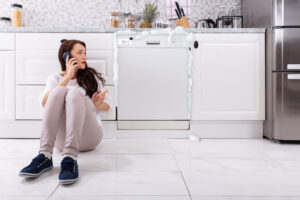 a woman on the phone with a technician as her dishwasher overflows because of bad DIY appliance repairs