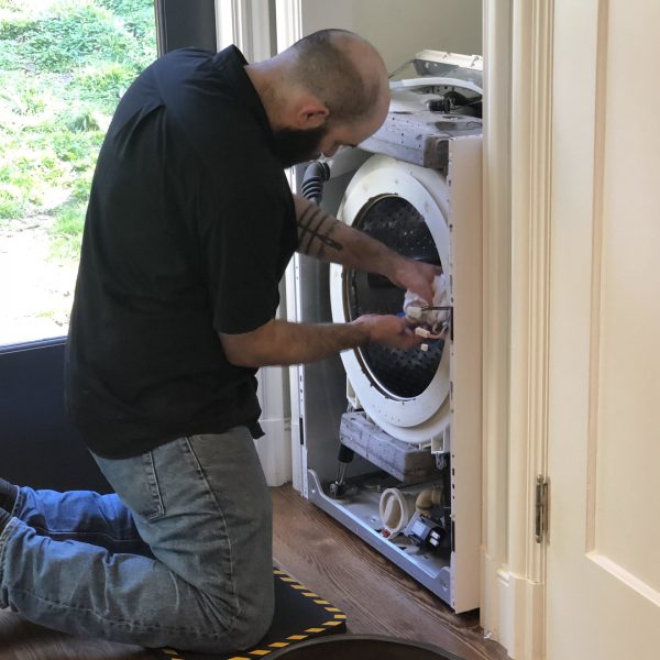 A technician repairing a broken washing machine