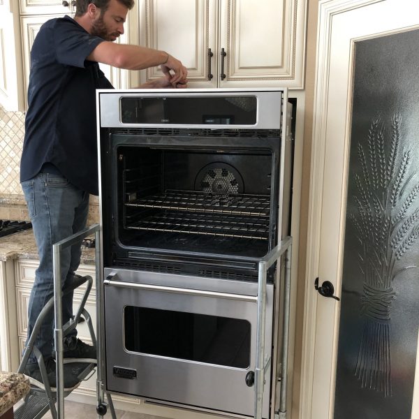 A technician performing a repair on an oven.