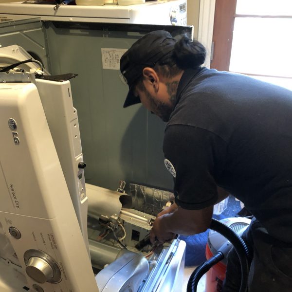 A technician repairing a gas dryer