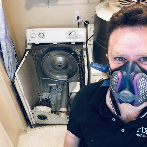 A technician standing in front of a dryer that needed maintenance.