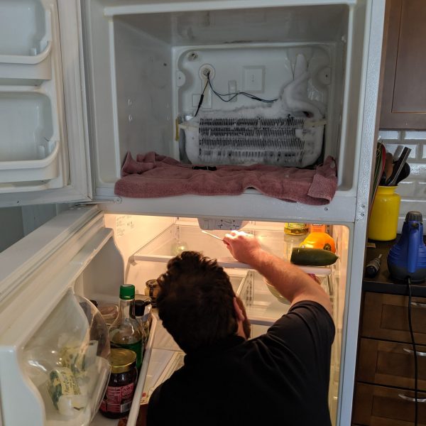 A technician repairing a leaking refrigerator.